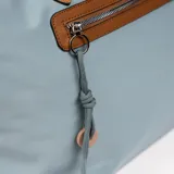Bolso tipo tote bag color gris azulado con detalles en marrón. Tiene doble asa de hombro marrón, cierre superior y bolsillo frontal con cierre.