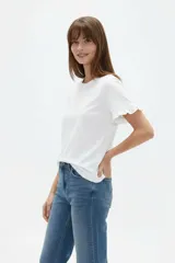 Remera blanca de algodón, de corte ajustado, con cuello redondo y mangas cortas terminadas con volados delicados.
