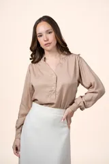 Blusa de tencel color beige con cuello mao, escote en V con botones frontales y mangas largas abullonadas.