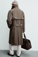 Trench de corte regular confeccionado en tejido técnico italiano repelente al agua. Presenta cuello con solapas de muesca, cierre frontal de botonadura cruzada, cinturón ajustable del mismo tejido, bolsillos de vivo en la cadera, manga larga con puños ajustables y abertura central en la espalda.