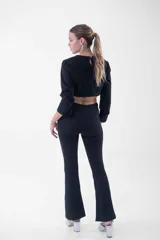 Pantalón negro de corte flare, tiro alto, con detalles de flecos de strass en los bolsillos laterales.
