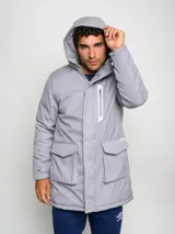 Parka larga gris con capucha, cierre frontal con cremallera y botones a presión, múltiples bolsillos y logo de Umbro en el pecho.