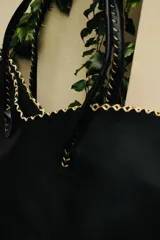 Cartera de cuero color marrón chocolate con manijas largas y borde superior en corte en V. Diseño amplio y liviano, con terminaciones artesanales y costuras contrastantes en todo el contorno.