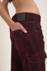 Pantalón jean cargo color borgoña, de pierna ancha y tiro medio, con múltiples bolsillos con solapa y broches.