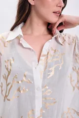 Camisa blanca de algodón con estampado de ramas doradas, de corte recto y mangas largas.