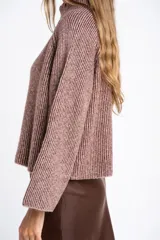 Sweater de tejido de punto con cuello alto, mangas largas y diseño holgado. Presenta un patrón de rayas verticales en tonos malva y beige.