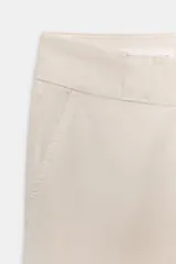 Pantalón de mujer color beige claro, tiro medio, con corte recto y ancho, confeccionado en algodón. Presenta bolsillos delanteros y bolsillos de vivo en la espalda, cintura con trabillas y cierre frontal con cremallera y gancho metálico.