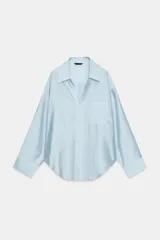 Camisa satinada de corte oversize color celeste, con cuello solapa, escote en V y bolsillo de parche en el pecho.