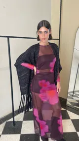 Ruana tejida de color negro con sutiles destellos plateados, diseño de líneas verticales y terminación con flecos largos en los extremos.