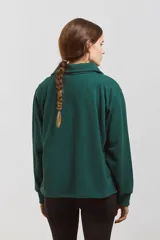 Buzo de algodón en color verde inglés, con diseño de cuello tipo chomba con botones frontales y detalles en blanco. Presenta un corte holgado y cómodo con mangas largas.