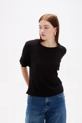 Remera negra de viscosa con textura acanalada, cuello redondo y mangas cortas terminadas en volados.