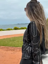 Chaqueta negra de cuero sintético con tachas plateadas, lentejuelas y strass.