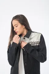 Campera de jean negra con detalles de cuero sintético plateado en la parte superior y tachas plateadas en los hombros.