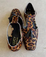 Mocasín negro de cuero vacuno, con punta cuadrada y detalle de borlas en el empeine.