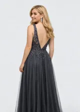 Vestido largo de fiesta confeccionado en tul, con escote en V y corset estructurado con aplicaciones de encaje y pedrería en el torso. Presenta una falda amplia y fluida con caída vaporosa.