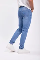 Pantalon jean de corte slim en color azul medio, con diseño clásico de cinco bolsillos y cierre frontal con botón y cremallera.