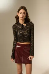 Top de encaje negro con mangas largas acampanadas, cuello mao con cierre de lazo frontal y diseño ajustado al cuerpo.