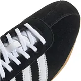 Championes Adidas modelo Tokyo, de diseño retro con exterior de gamuza negra, las icónicas tres tiras laterales en blanco y suela de goma color caramelo. Incluye el logo de la marca y el nombre del modelo en dorado en el lateral.