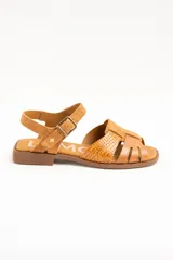 Sandalias planas de cuero color caramelo, con tiras entrelazadas en la parte delantera y tira ajustable con hebilla metálica en el tobillo.