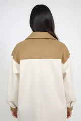 Sobre camisa de corte oversize en combinación de colores natural y camel. Presenta cuello clásico, cierre frontal con botones, mangas largas con puños en contraste y dos bolsillos frontales con solapa y botón.