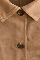 Camisa de manga larga en tejido con acabado tipo gamuza, de corte holgado con cuello clásico, cierre frontal de botones y puños abotonados. Presenta costuras decorativas visibles y bajo redondeado.