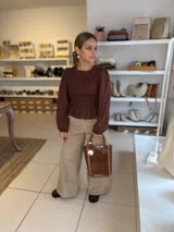 Blusa color chocolate con diseño de frunces elásticos en el frente y la espalda, mangas largas abullonadas con puños elásticos y corte peplum.