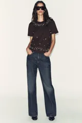 Camiseta de manga corta y cuello redondo, color marrón oscuro, con apliques de perlas de diferentes tamaños distribuidos en el escote y el bajo.