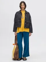 Campera de denim color negro con diseño de flecos en la parte frontal, cuello camisero y cierre frontal con botones metálicos.