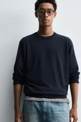 Jersey de punto color azul marino, con cuello redondo y manga larga. Presenta acabados en rib en cuello, puños y bajo.
