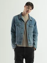 Campera de jean celeste de corte clásico con cuello camisero, cierre frontal con botones metálicos, bolsillos con solapa abotonada en el pecho y bolsillos laterales. Confeccionada en denim de algodón y poliéster.