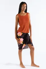 Musculosa tejida en punto canalé con mezcla de viscosa y hilos metálicos Lurex color naranja, con escote bote y sin mangas.
