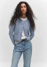 Cardigan de punto con textura en relieve, color azul, de corte recto y corto. Presenta manga larga, cuello redondo y cierre frontal con botones efecto joya.
