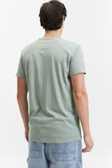 Remera verde con escote en V y logo bordado en el pecho.