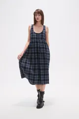 Vestido midi sin mangas confeccionado en algodón con estampado de cuadros en tonos azul y negro. Presenta un diseño holgado con cuello redondo y cierre posterior.