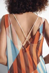Vestido midi de tirantes con diseño geométrico y de rayas verticales en tonos salmón, celeste, marrón y blanco. Cuenta con escote en V y tirantes cruzados en la espalda.