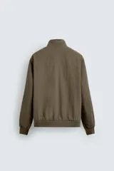 Cazadora azul marino de corte regular fit, confeccionada en tejido técnico repelente al agua. Presenta cuello subido, manga larga, bolsillos de vivo en cadera, bolsillo interior y acabados en rib en puños y bajo. Cierre frontal de cremallera oculta por solapa con botones a presión.