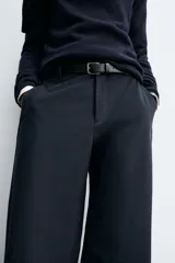 Pantalón de corte balloon fit, color negro, con bolsillos laterales de vivo y bolsillos traseros con solapa. Presenta cierre frontal con cremallera y botón.