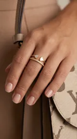 Anillo doble de acero con baño de oro, compuesto por una banda con circonias engastadas y otra banda abierta con extremos decorados con nácar en forma de gota.