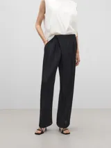 Pantalón negro con textura arrugada, corte holgado y cierre con botón.