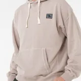 Canguro Rip Curl Aots Ty Willmians color beige, con capucha ajustable con cordones blancos, bolsillo canguro frontal y parche cuadrado con diseño en el pecho.