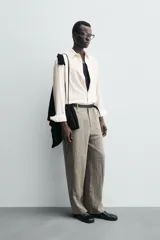 Camisa de hombre de corte relajado (relaxed fit) en tejido de mezcla de algodón y viscosa, color beige claro con finas rayas verticales. Presenta cuello italiano y manga larga con puño abotonado.