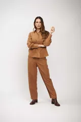 Camisa de manga larga color tostado, con cuello clásico y cierre frontal de botones. Presenta un diseño de corte recto y acabado suave.