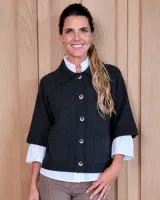 Cardigan de lana lambswool color gris oscuro, con cuello clásico, cierre frontal de botones y mangas cortas con terminación acanalada. Presenta dos bolsillos frontales y diseño de punto liso.