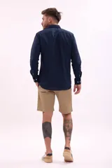 Camisa de manga larga color beige, con cuello clásico y botones frontales.