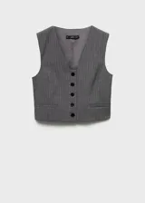 Chaleco de corte crop y diseño recto con cuello en pico y cierre frontal de botones. Presenta un estampado de raya diplomática y cuenta con forro interior y detalle de cinta en la parte posterior.