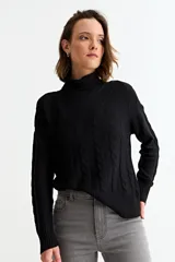 Sweater negro de cuello alto con diseño de tejido trenzado vertical y textura geométrica. Presenta mangas largas con puños acanalados y un corte holgado.