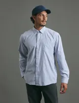 Camisa de manga larga con estampado de rayas verticales en azul y blanco, cuello clásico y bolsillo frontal.