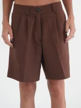 Bermuda negra de tiro medio, corte ancho, con bolsillos laterales y un ojal en la parte trasera.