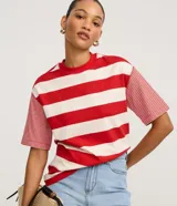 Remera t-shirt de algodón con cuello redondo, mangas cortas y rayas horizontales rojas y blancas, destacando por las mangas con rayas más finas y costuras aparentes en las sisas.