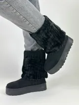 Botas negras de caña media con plataforma y detalle de piel sintética en la parte superior.